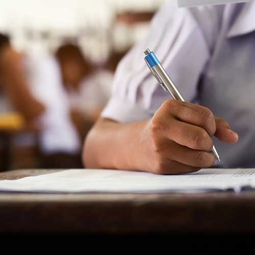 Image of a student writing on a paper representing Escolarizada modality